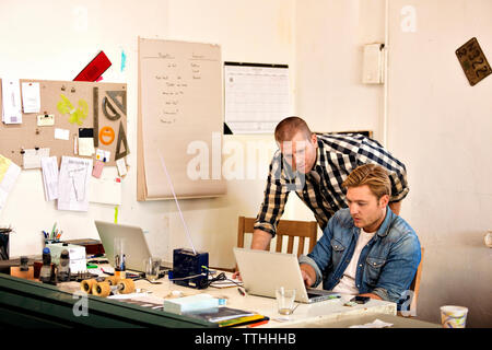 Male carpenter looking at laptop while working in workshop Stock Photo
