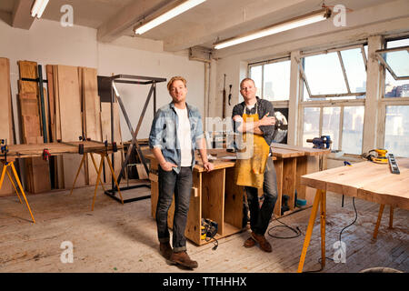 Portrait of male carpenter standing by wood in workshop Stock Photo