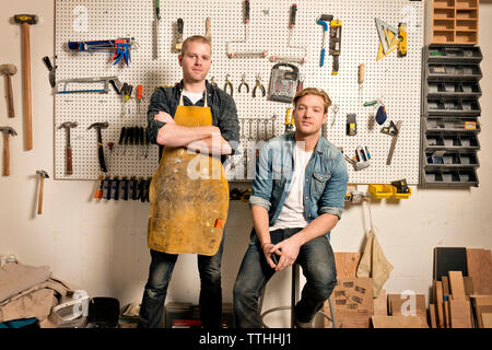 Portrait of male carpenters against wall with tools in workshop Stock Photo