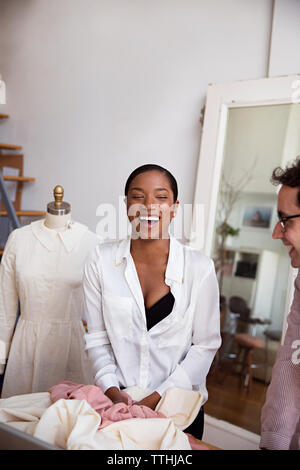 Cheerful fashion designers standing at desk in studio Stock Photo
