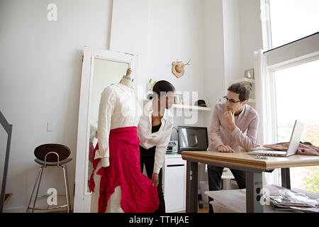 Fashion designer showing dress on model to colleague Stock Photo