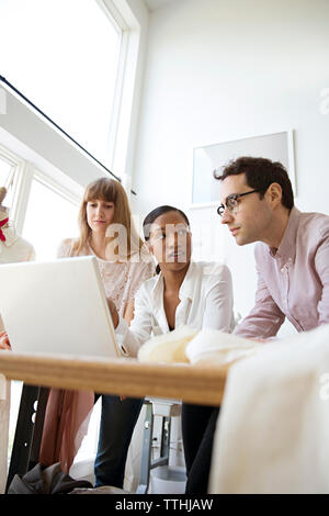 Fashion designers discussing over laptop at desk Stock Photo