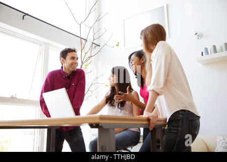 Happy business colleagues having discussion over laptop at table Stock Photo