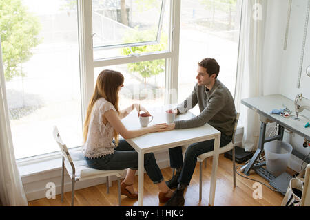 High angle view of colleagues discussing while having coffee at table Stock Photo