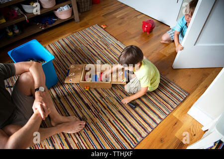 High angle view of father sitting by boys playing at home Stock Photo