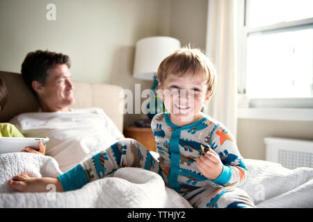 Happy boy enjoying with father while brother using tablet computer on bed at home Stock Photo