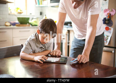 Father assisting son in using tablet computer at home Stock Photo