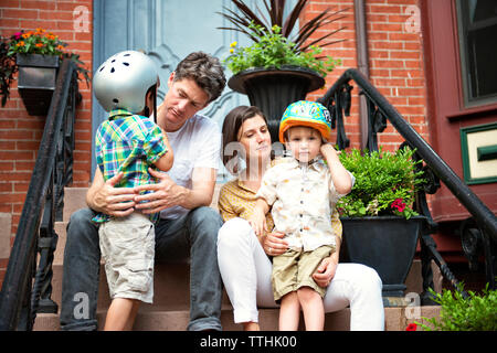 Family sitting on steps outside house Stock Photo