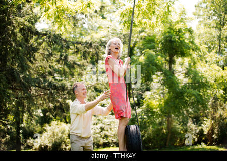 Happy senior couple playing on swing at park Stock Photo