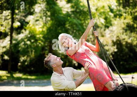 Cheerful senior couple playing on swing at park Stock Photo