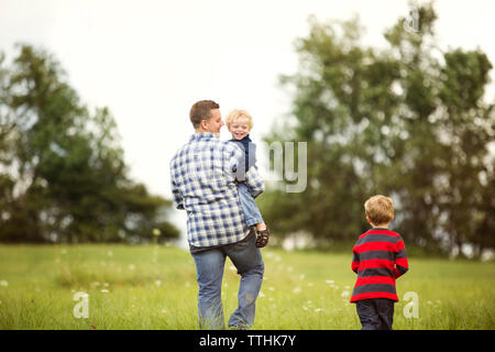 Happy father with sons on grassy field Stock Photo