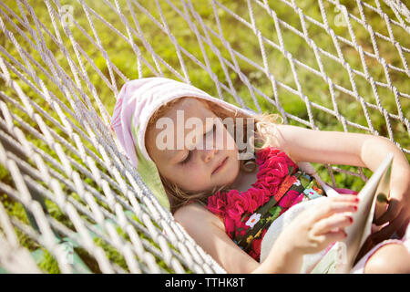 Girl lying in hammock and reading a book Stock Photo - Alamy