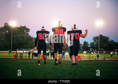 Smiling group of young American football players walking onto a grassy  field together on a sunny afternoon during a football game Stock Photo -  Alamy