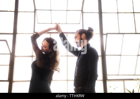 Young couple dancing against window on sunny day Stock Photo