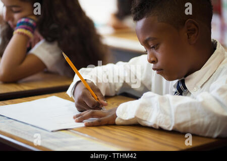 Boy sitting at desk during test in classroom Stock Photo
