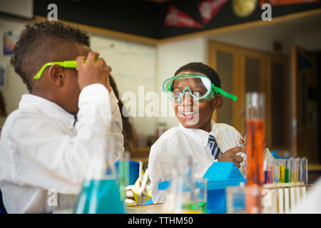 Happy boy wearing protective eyewear while looking at friend in laboratory Stock Photo