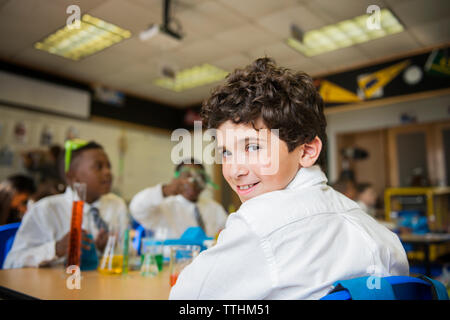 Portrait of smiling boy sitting at table in laboratory Stock Photo