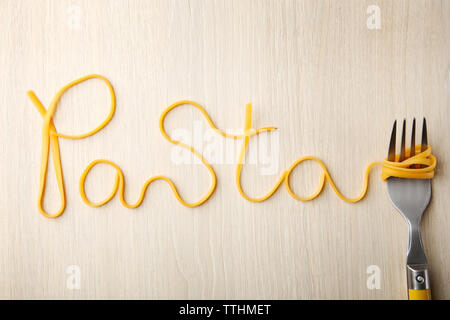 Word PASTA made of cooked spaghetti with fork on wooden background Stock Photo