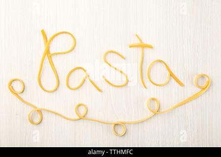 Word PASTA made of cooked spaghetti on wooden background Stock Photo