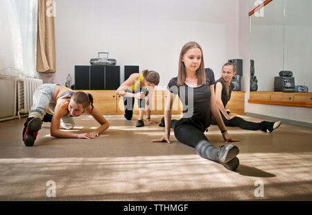 Female friends stretching on floor at home Stock Photo