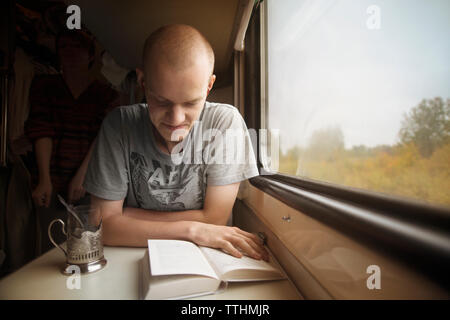 Man reading book while travelling in train Stock Photo
