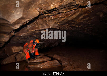Manual worker cleaning boot while sitting in cave Stock Photo
