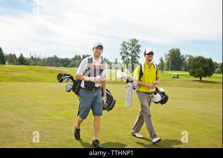 Male friends walking on golf course Stock Photo