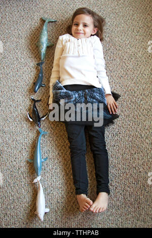 High angle view of girl lying by toys on carpet Stock Photo