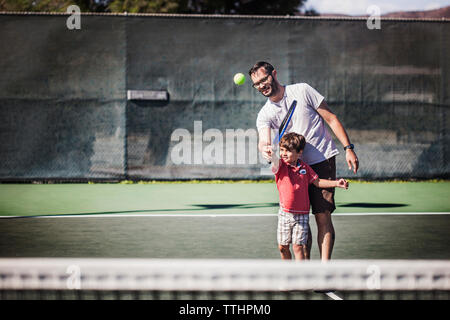 Father and son playing tennis on court Stock Photo