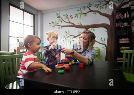 Teacher playing with children at preschool Stock Photo