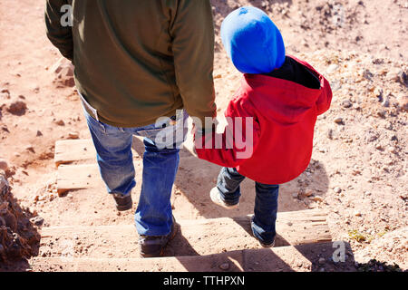 High angle view of father holding son's hand while walking on steps at beach Stock Photo