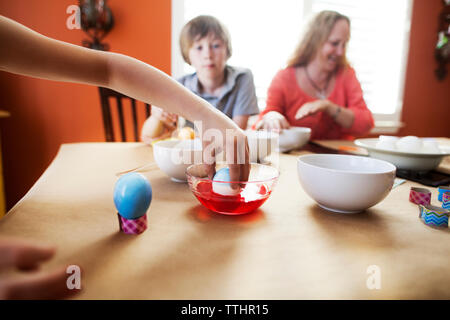 Cropped image of girl decorating easter eggs with family at home Stock Photo