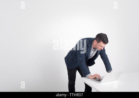 businessman working on laptop computer while standing at table Stock Photo
