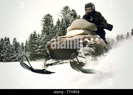 Man riding snowmobile on snow field in forest Stock Photo