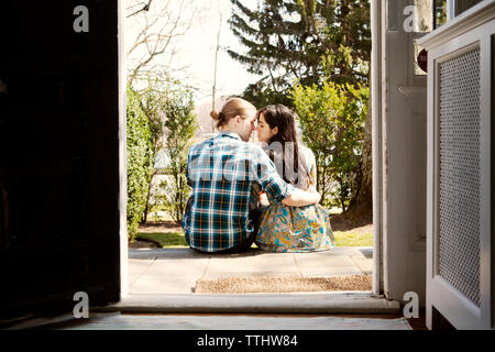 Rear view of couple sitting on front stoop Stock Photo