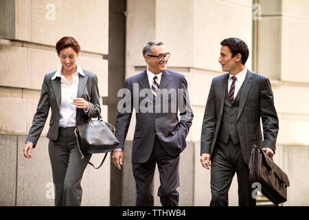 Happy business people walking on city street Stock Photo