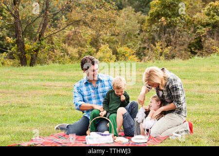Happy family enjoying picnic on grassy field Stock Photo