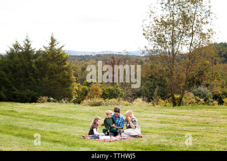 Family enjoying picnic on grassy field Stock Photo