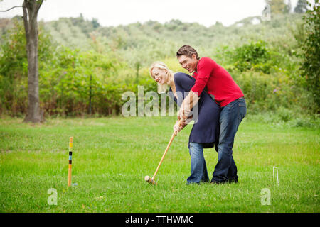 Couple playing croquet on grassy field Stock Photo