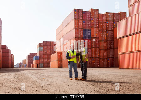 Dock Workers discussing while standing on road by cargo containers at commercial dock Stock Photo