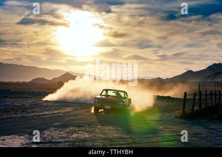 Man driving car on field during sunset Stock Photo