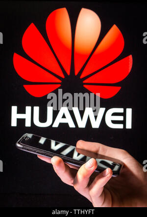 A man using a mobile phone in front of the Huawei sign (editorial use only) Stock Photo