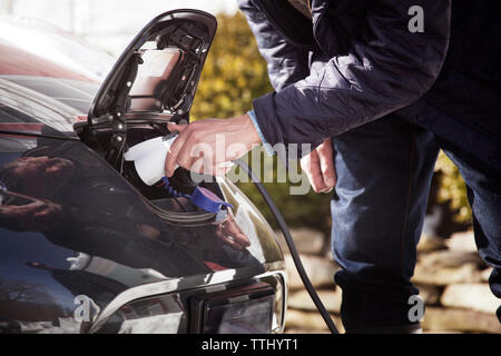 Midsection of man charging electric car Stock Photo