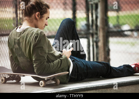 Man using smart phone while relaxing on seat at skateboard park Stock Photo