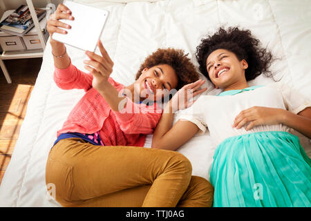 High angle view of siblings photographing while lying on bed at home Stock Photo
