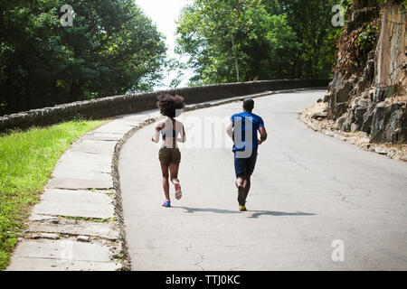 Rear view of couple jogging on road Stock Photo