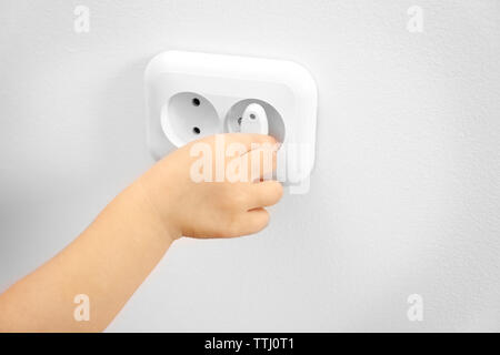 Little child putting plug in power socket Stock Photo