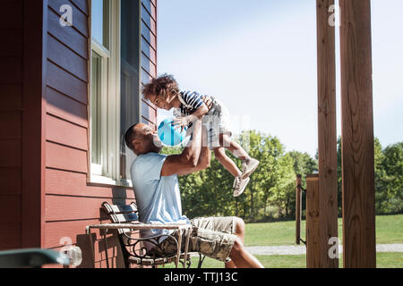 Happy father lifting boy while sitting at backyard Stock Photo