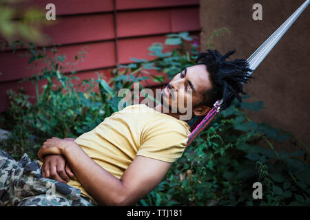 Man looking away while relaxing on hammock in lawn Stock Photo