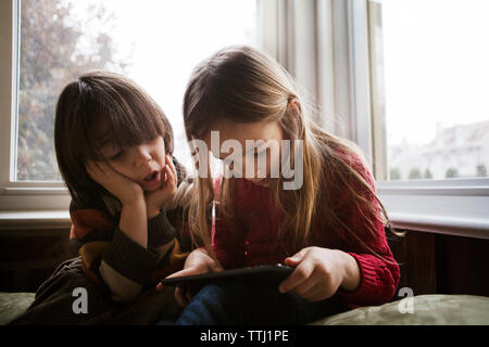 Boy looking at sister using tablet computer at home Stock Photo